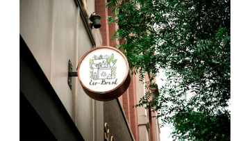 Logo van Eco-Box.nl op een ronde winkelbord in een groene stadsomgeving