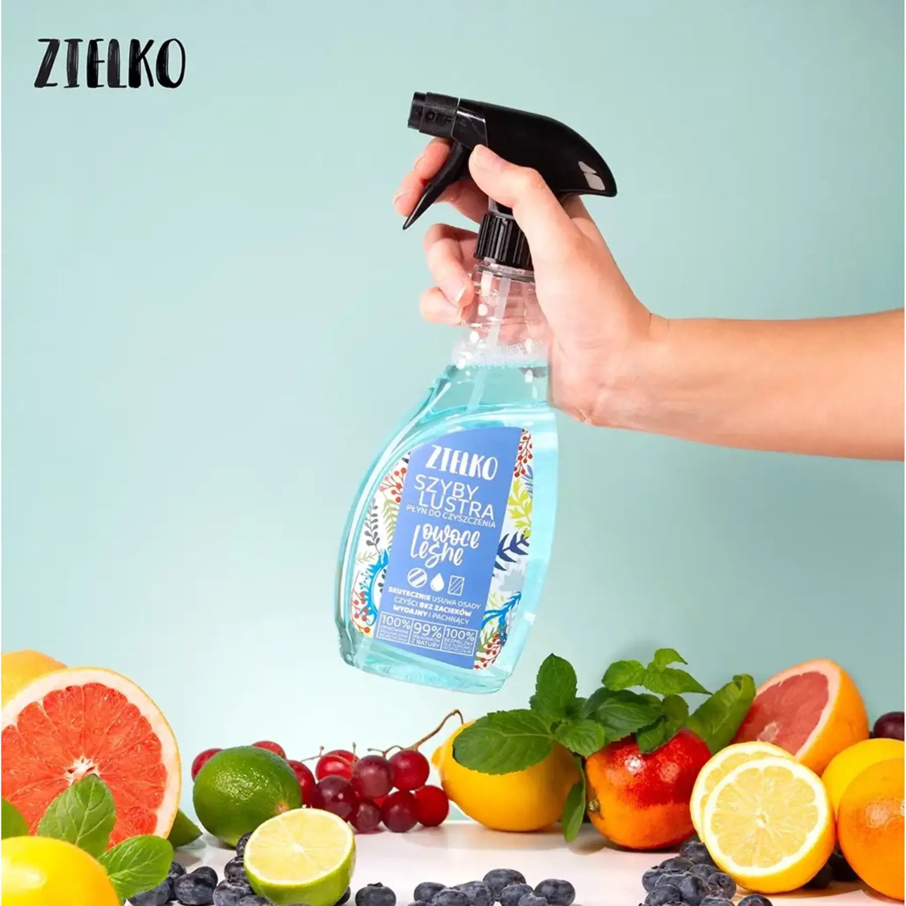 Hand houdt ZIELKO glas- en spiegelreiniger bosvruchten tussen kleurrijk fruit, natuurlijke frisse geur.